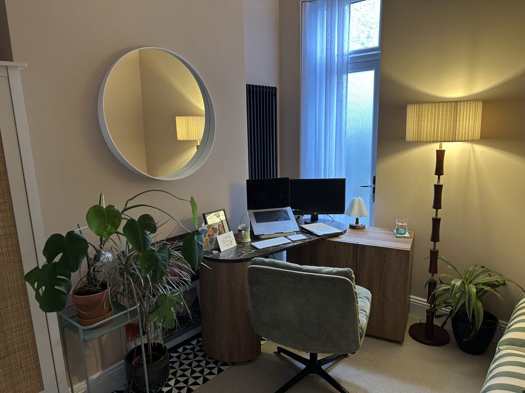 A quiet corner of the therapy room with a desk, plants and a round mirror